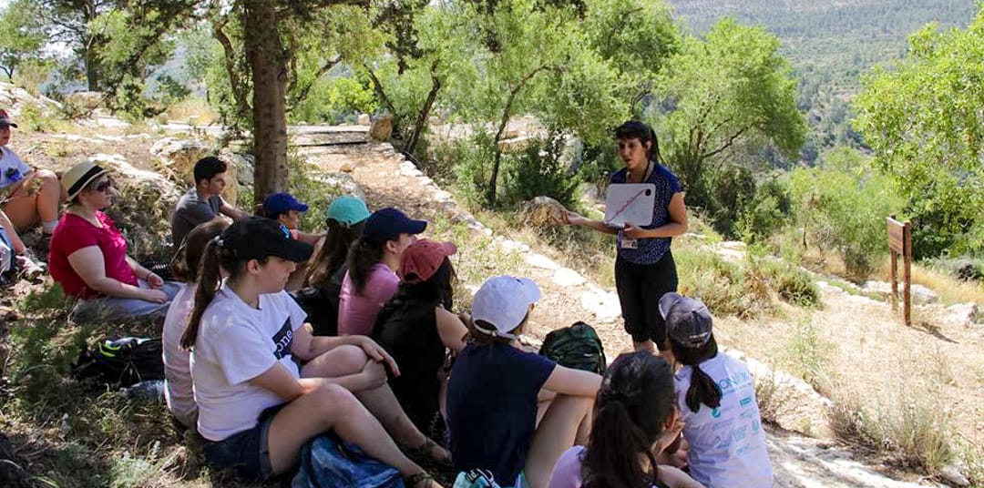 Young Judaea staff instructing teen on hillside